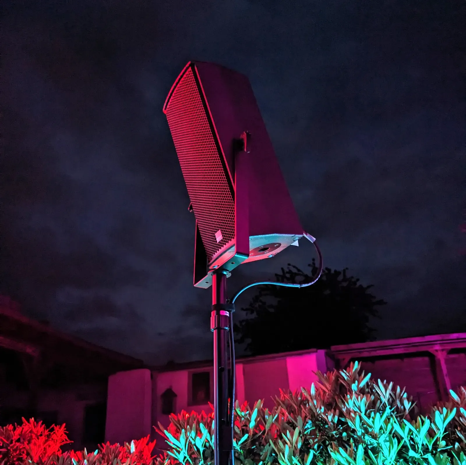 Lautsprecher auf einem Stativ bei Nacht in farbigem Licht